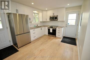 Guelph/Eramosa (Rockwood) fourplex for rent - A kitchen with white cabinets and a stainless steel refrigerator.