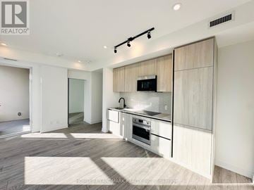 Toronto (Waterfront Communities) condo for rent - A modern kitchen with a white countertop and a microwave built into it.