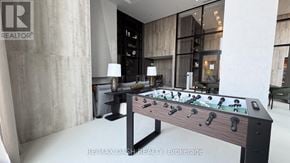 Vaughan (Steeles West Industrial) condo for rent - A foosball table is in the middle of a room with a REALTOR sign on the wall.