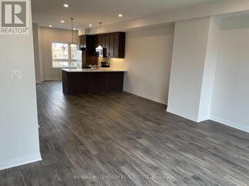 Cambridge townhouse for rent - A spacious room with a wooden floor and a kitchen area with a counter and cabinets.