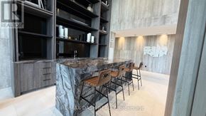 Vaughan (Steeles West Industrial) condo for rent - A modern kitchen with a marble island and wooden chairs.