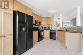 Oakville (Wm Westmount) townhouse for rent - A kitchen with black appliances and wooden cabinets.