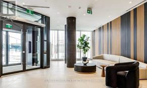 Oshawa (Windfields) condo for rent - A modern office lobby with a glass door entrance, a white sofa, and a black chair.