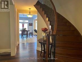 Aurora apartment for rent - A wooden staircase with a glass railing and a table with a vase of flowers on it.