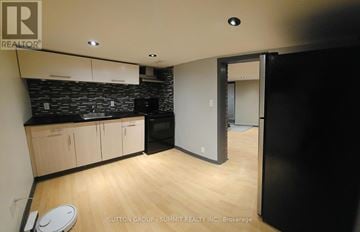 Toronto (The Beaches) triplex for rent - A kitchen with wooden floors and a black counter top.