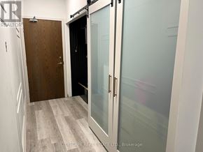 Toronto (Regent Park) condo for rent - A hallway with a wooden door and a glass door.