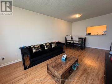 Toronto (Woburn) condo for rent - A living room with a black couch and wooden coffee table.