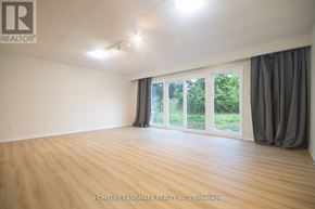 Toronto (Newtonbrook West) apartment for rent - A room with wooden flooring and sliding glass doors leading to a green outdoor area.