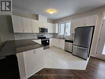 Ottawa townhouse for rent - A kitchen with white cabinets and a black fridge.