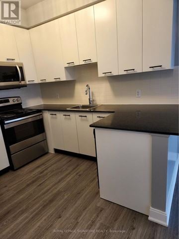 Toronto (Agincourt South-Malvern West) condo for rent - A kitchen with white cabinets and a black countertop.