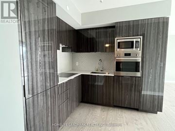 Toronto (Bay Street Corridor) condo for rent - A modern kitchen with dark wood cabinets and stainless steel appliances.