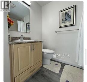Richmond apartment for rent - A bathroom with a toilet, sink, and a mirror.
