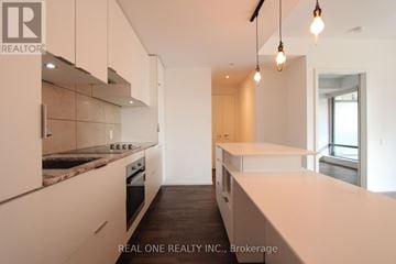 Toronto (Bay Street Corridor) condo for rent - A modern kitchen with white cabinets and a marble countertop.