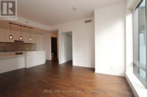 Toronto (Bay Street Corridor) condo for rent - A spacious room with wooden floors and white walls, with a bar area in the corner.