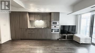 Toronto (Bay Street Corridor) condo for rent - A spacious living room with a grey sofa and a television.