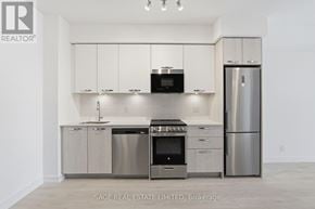 Hamilton (Corktown) condo for rent - A modern kitchen with stainless steel appliances and white cabinets.