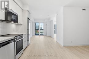 Hamilton (Corktown) condo for rent - A white kitchen with a black microwave and stove.