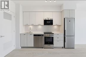 Hamilton (Corktown) condo for rent - A modern kitchen with stainless steel appliances and white cabinets.