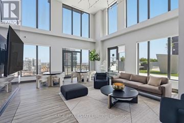 Hamilton (Corktown) condo for rent - A living room with a black couch and a wooden floor.