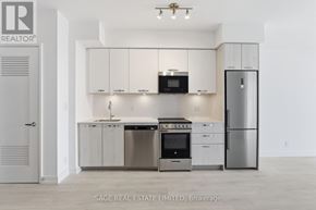 Hamilton (Corktown) condo for rent - A modern kitchen with stainless steel appliances and white cabinets.