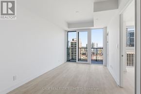 Hamilton (Corktown) condo for rent - A large, empty room with a view of the city through the windows.
