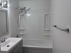 Lloydminster apartment for rent - A white bathroom with a sink, mirror, and bathtub.
