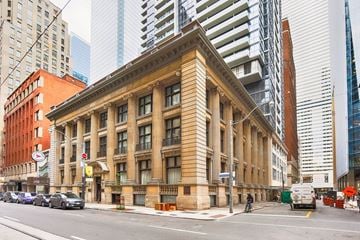 Toronto apartment for rent - A large, old-fashioned building with a brown facade is situated on a street corner.