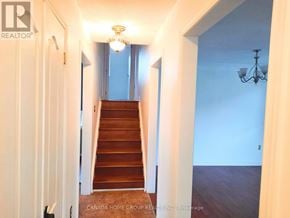 Barrie (Painswick North) apartment for rent - A hallway with a staircase leading to a landing with a chandelier.