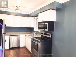 Barrie (Painswick North) apartment for rent - A kitchen with white cabinets and a black stove top oven.