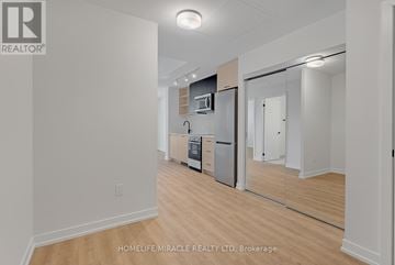 Toronto (Junction Area) condo for rent - A kitchen with a refrigerator, microwave, and oven is shown in a real estate listing.