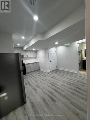 Halton Hills (Georgetown) apartment for rent - A room with a grey floor and white walls, with a black refrigerator on the left side.