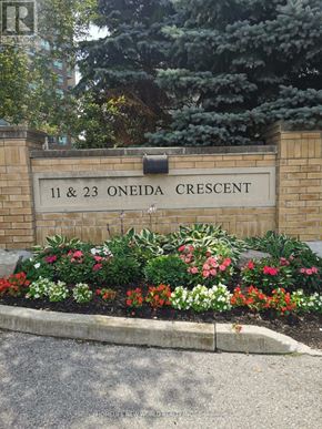 Richmond Hill (Langstaff) condo for rent - A sign that says 11 & 23 Oneida Crescent is in front of some trees.