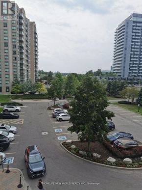 Richmond Hill (Langstaff) condo for rent - A parking lot with cars and a tree in the middle.