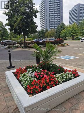 Richmond Hill (Langstaff) condo for rent - A flower bed in the foreground with a sign that says HomeLife New World Realty Inc. Broverage.