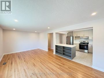 Ottawa multi-family for rent - A spacious room with wooden flooring and a kitchen area in the background.