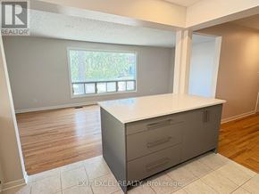 Ottawa multi-family for rent - A room with a large island in the middle and a window with a view of trees.