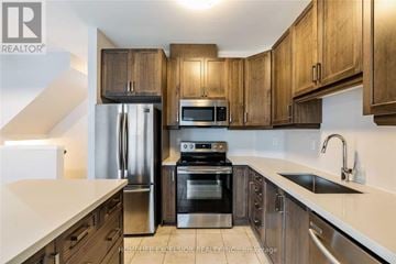 Hamilton (Stoney Creek) townhouse for rent - A kitchen with wooden cabinets and stainless steel appliances.