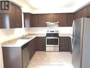 Oshawa (Windfields) townhouse for rent - A kitchen with brown cabinets and a stainless steel refrigerator.