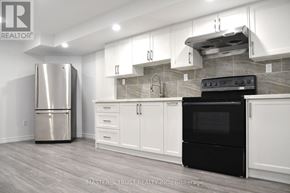 Markham (Cedar Grove) apartment for rent - A kitchen with a stainless steel refrigerator, black oven, and white cabinets.