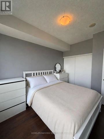 Toronto (North St. James Town) condo for rent - A bedroom with a bed, nightstand, and a round mirror on the wall.