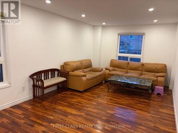 Markham (Milliken Mills East) apartment for rent - A living room with a brown sofa and a wooden chair.