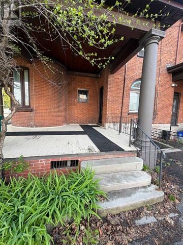 Belleville (Belleville Ward) fourplex for rent - A red brick building with a black railing and a tree in front.