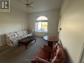 Belleville (Belleville Ward) fourplex for rent - A living room with a floral sofa, a round table, and a ceiling fan.