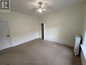 Belleville (Belleville Ward) fourplex for rent - A carpeted room with a ceiling fan and a door in the background.