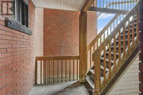 Hamilton (Stinson) condo for rent - A wooden staircase with a railing leads up to a window on a brick wall.