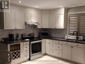 Niagara Falls (Ascot) apartment for rent - A kitchen with white cabinets and black countertops.