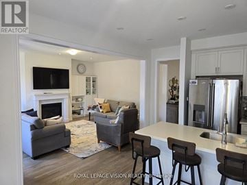 Whitby (Rolling Acres) apartment for rent - A well-lit, modern kitchen and living room with a grey sofa and bar stools.