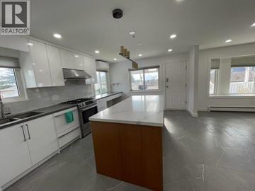 Vancouver apartment for rent - A modern kitchen with white cabinets and a central island.