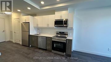 Kitchener townhouse for rent - A kitchen with white cabinets and stainless steel appliances.