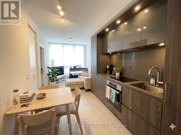 Toronto (Waterfront Communities) condo for rent - A modern kitchen with wooden cabinets and a dining table.